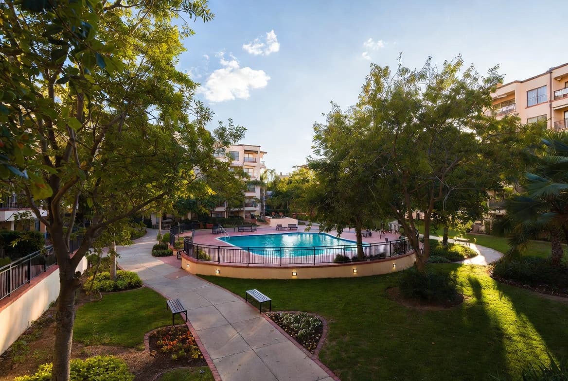 HOA pool surrounded by mature trees and landscaping