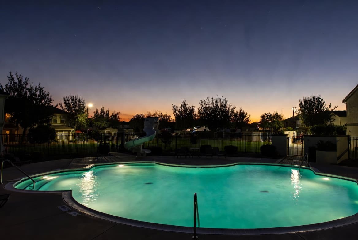 Beautiful HOA community pool glowing at dusk with surrounding homes
